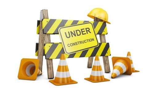 Under Construction sign with hard hat, and orange cones